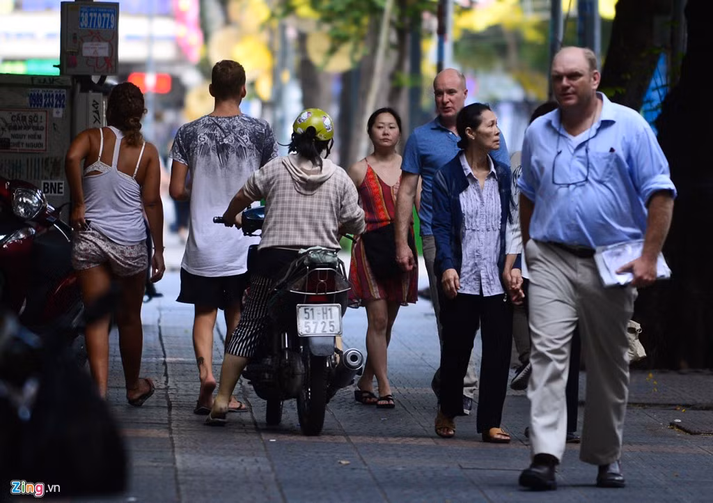 Một người phụ nữ chạy xe máy chen vào dòng người đi bộ trên đường Đồng Khởi.