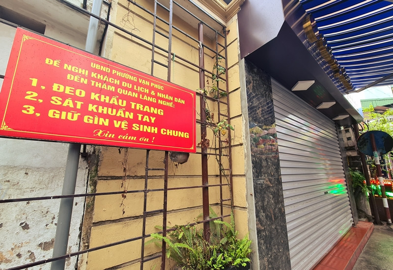 Để phòng chống dịch bệnh COVID-19, UBND phường sở tại treo nhiều tấm biển thông báo xung quanh làng lụa Vạn Phúc, yêu cầu khách và nhân dân phải đeo khẩu trang, sát khuẩn, giữ vệ sinh chung khi đến đây.