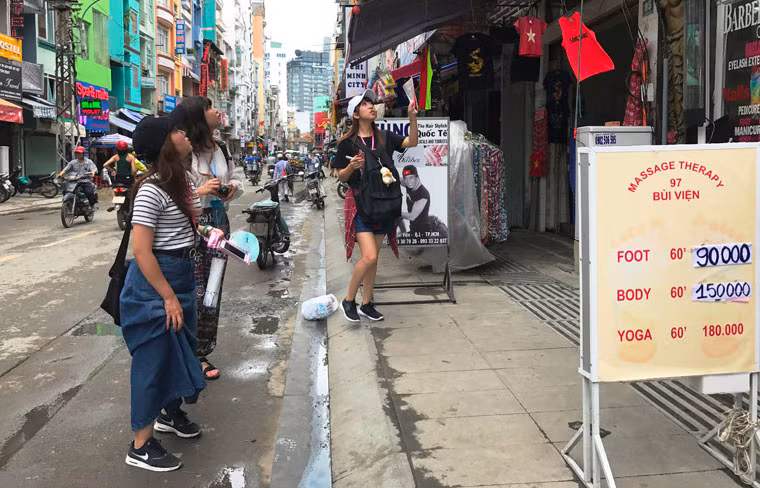 Du khách quốc tế thích thú dạo trên tuyến đường Bùi Viện vào trưa 18/8.