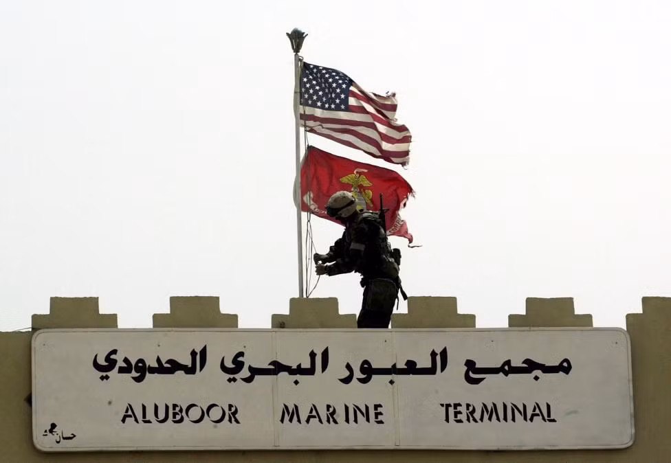 Một binh sĩ Mỹ thay cờ Iraq trên nóc cánh cổng ra vào cảng Umm Qasr hôm 21/3/2003.