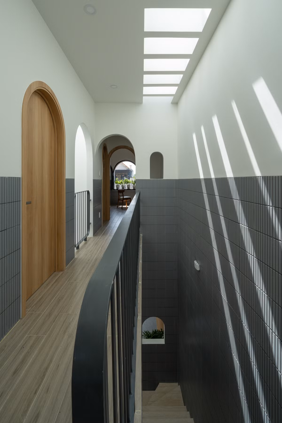 Tầng 2 gồm 3 phòng ngủ và một nhà vệ sinh chung. Hai tầng này kết nối với nhau qua giếng trời lớn giữa nhà, kết hợp mảng xanh nhỏ. Ảnh: Quang Trần