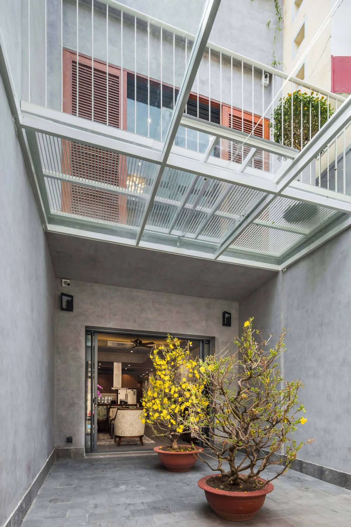 Sân nhỏ để xe và đặt cây cảnh cũng là khoảng đệm trước khi bước vào phòng khách. Ảnh: DeconPhotoStudio