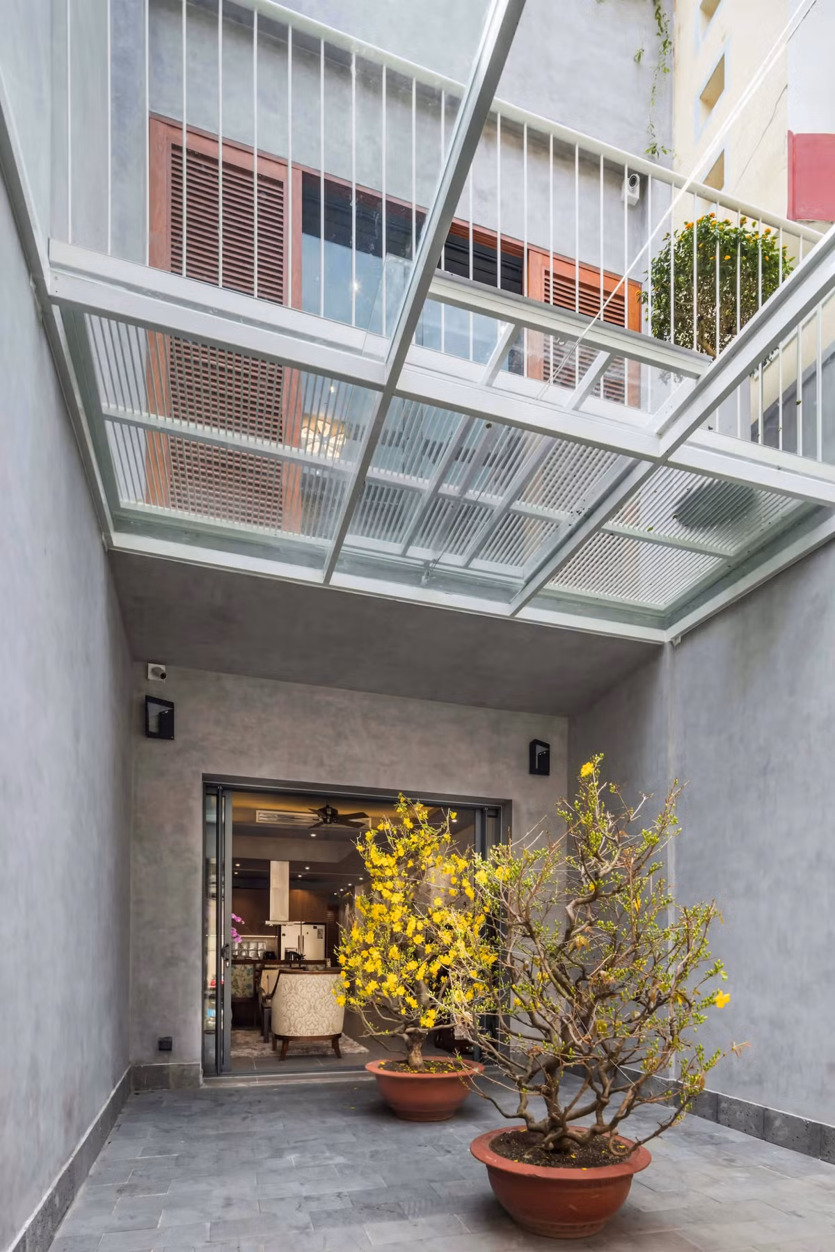 Sân nhỏ để xe và đặt cây cảnh cũng là khoảng đệm trước khi bước vào phòng khách. Ảnh: DeconPhotoStudio