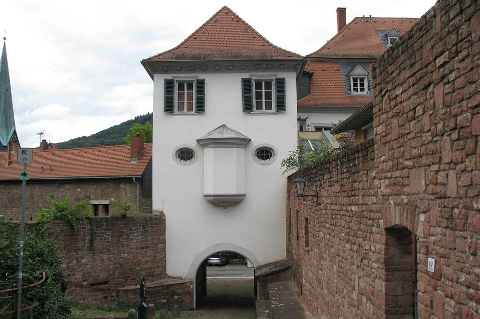 Phần mở vòm ở chân của ngôi nhà bất thường này trông giống như một cái miệng cụt xuống. Kết hợp với một vật trang trí nổi bật giống như mũi và hai cửa sổ hình ô van tựa như mắt, ngôi nhà có vẻ buồn. Ảnh: Wiki