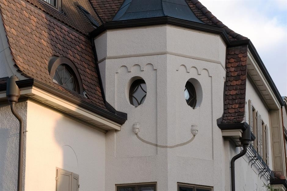 Ngôi nhà nằm tại Thụy Sĩ có cửa sổ hình bầu dục xinh xắn và các chi tiết trang trí giống như miệng và lông mày. Nhìn ngôi nhà trông giống khuôn mặt trẻ thơ đang mỉm cười nhìn xuống phố. Ảnh: Shutterstock