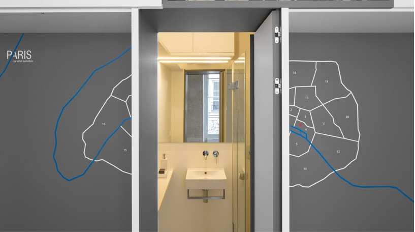 Giữa hai chiếc giường là một cánh cửa màu xám, mở ra là phòng tắm ẩn, có thể thay đổi định dạng. Ảnh: Designboom