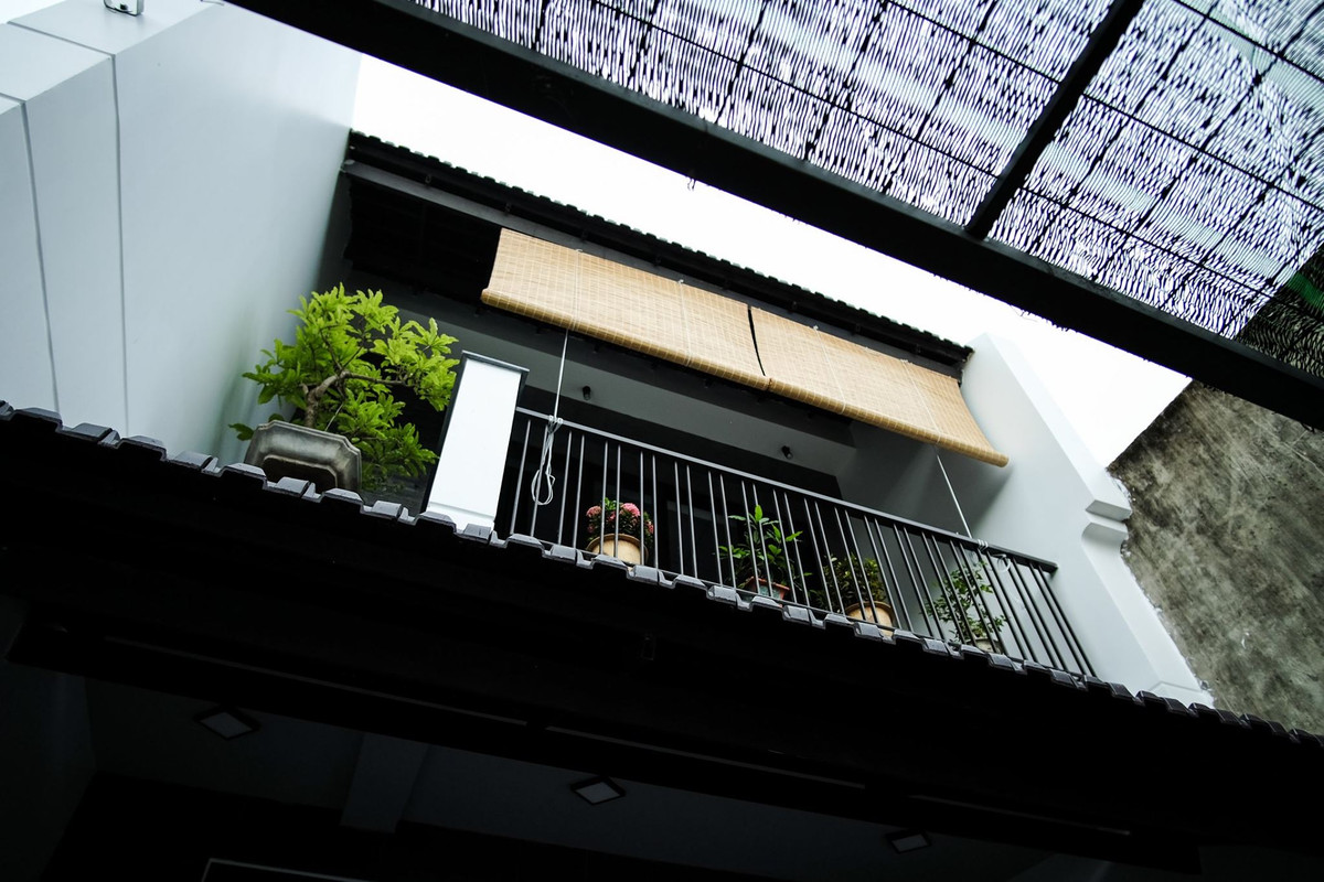 Do nhà phố hướng Đông - Đông Nam nên kiến trúc sư bố trí tường phía Nam ra ngoài, giúp che chắn và tạo bóng mát cho phần mặt tiền trong khoảng từ 9 - 10 giờ sáng. Tường bên phải được trang trí theo phong cách Hội An. Ảnh: Luân Nguyễn