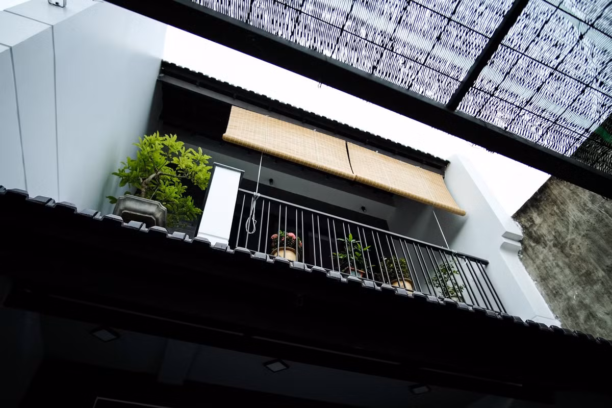 Do nhà phố hướng Đông - Đông Nam nên kiến trúc sư bố trí tường phía Nam ra ngoài, giúp che chắn và tạo bóng mát cho phần mặt tiền trong khoảng từ 9 - 10 giờ sáng. Tường bên phải được trang trí theo phong cách Hội An. Ảnh: Luân Nguyễn