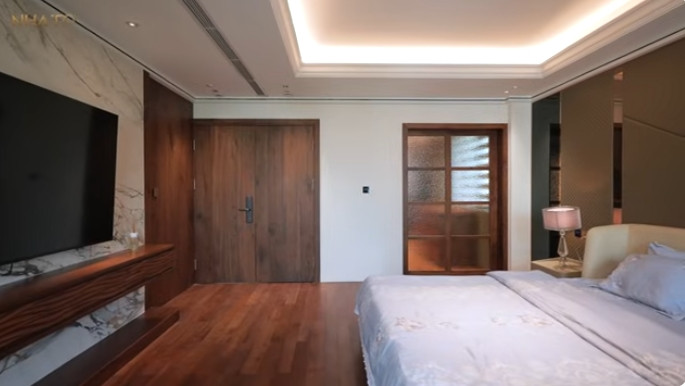 Phòng ngủ master tại tầng 2 được đầu tư lớn với toàn bộ nội thất bằng gỗ óc chó. Ảnh chụp màn hình NhaTo