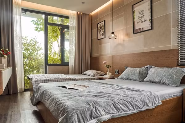 Phòng ngủ có cửa kính mở ra ban công cây xanh, ánh sáng ngập tràn. Ảnh: Phú Đào Studio
