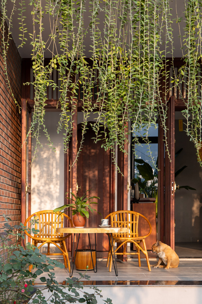 Do mặt tiền hướng Tây nên nhóm kiến trúc sư đã bố trí hiên nhà đóng vai trò là không gian đệm chuyển tiếp giữa bên trong và bên ngoài đồng thời là không gian giảm nhiệt cho phòng khách bằng hàng cây che bóng mát. Ảnh: Hoàng Lê