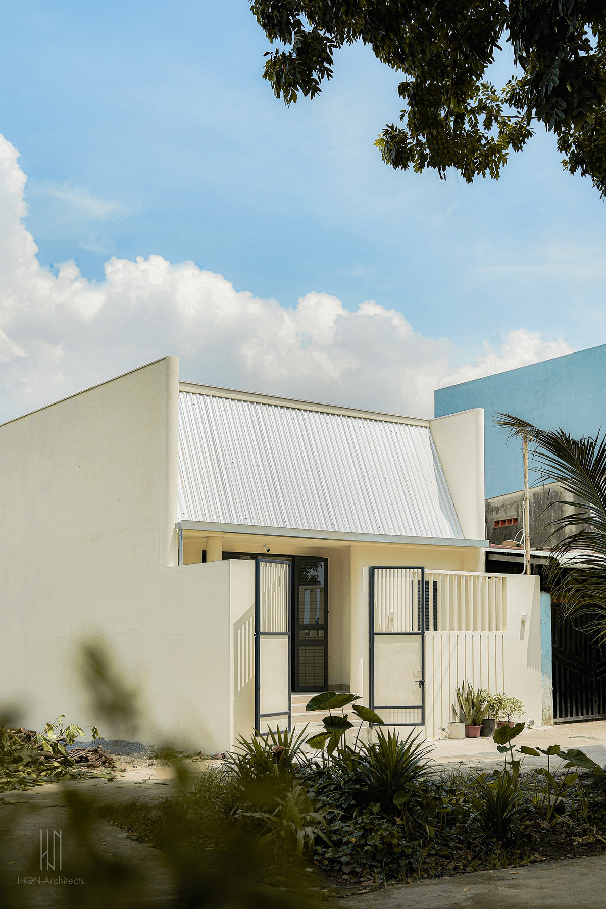 Ở bên ngoài, ngôi nhà 1 tầng nổi bật với hình khối mạnh mẽ, sơn trắng để hài hòa với bối cảnh xung quanh. Ảnh: Nam Vo/HQN-Architects