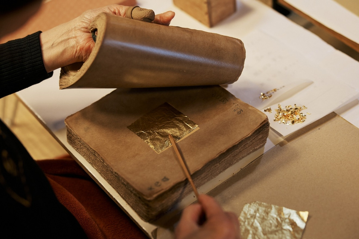 Quy trình tạo nên những lá vàng siêu mỏng trải qua nhiều công đoạn tỉ mỉ. Người thợ thủ công ngâm giấy ganpishi truyền thống trong hỗn hợp đặc biệt, rồi kẹp vàng giữa những tờ giấy để cán mỏng. Ảnh: Visitkanazawa