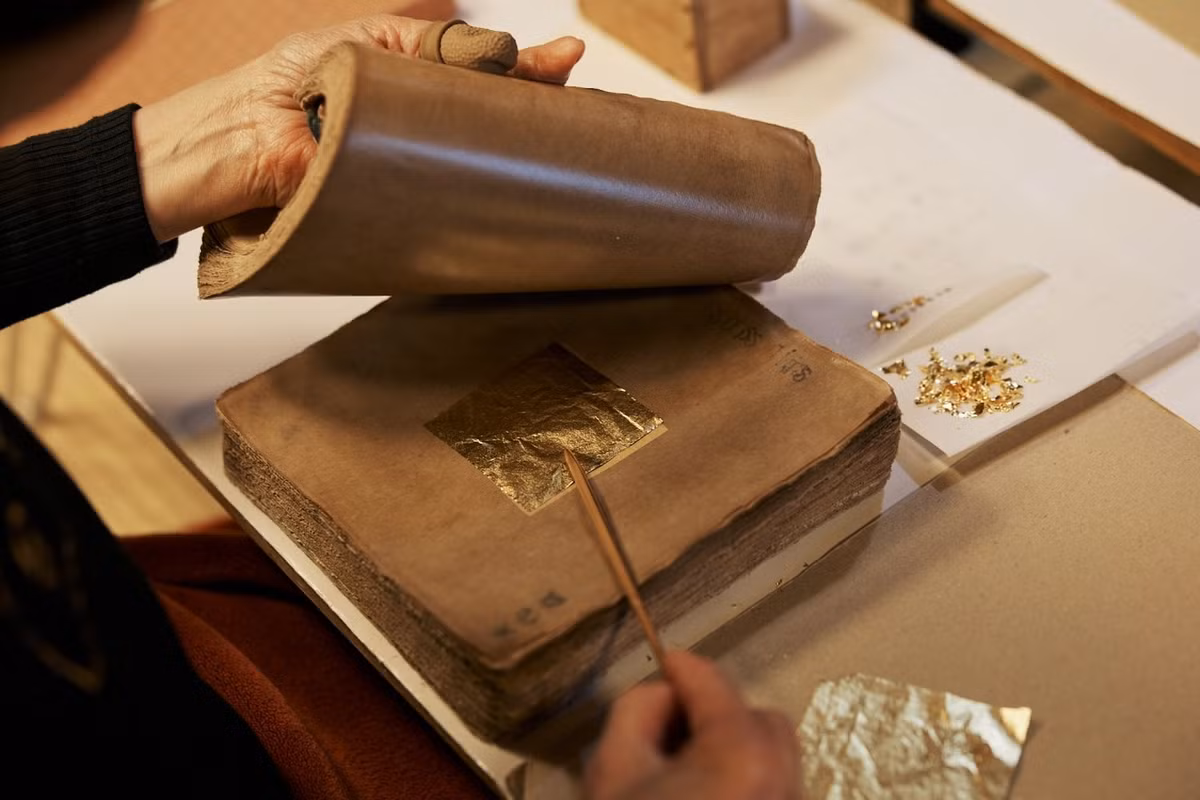 Quy trình tạo nên những lá vàng siêu mỏng trải qua nhiều công đoạn tỉ mỉ. Người thợ thủ công ngâm giấy ganpishi truyền thống trong hỗn hợp đặc biệt, rồi kẹp vàng giữa những tờ giấy để cán mỏng. Ảnh: Visitkanazawa