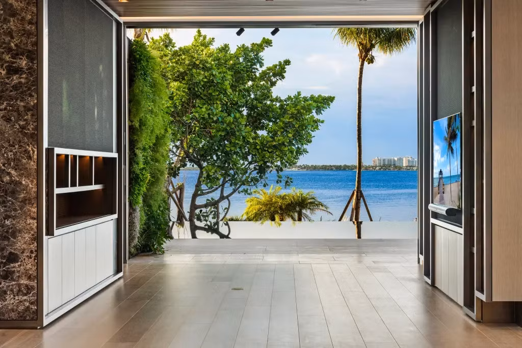 Phòng sinh hoạt ở tầng 1 có cửa kính từ sàn đến trần mở ra sàn gỗ và hồ bơi. Ảnh: Pagesix