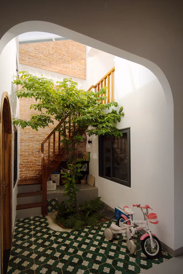 Hướng cầu thang lên lửng là hành lang ngập tràn ánh sáng được nhận từ khu vườn thông tầng xuống tầng trệt, kết hợp hệ cửa lam lấy gió đối lưu các không gian trong nhà. Ảnh: Greenconcept