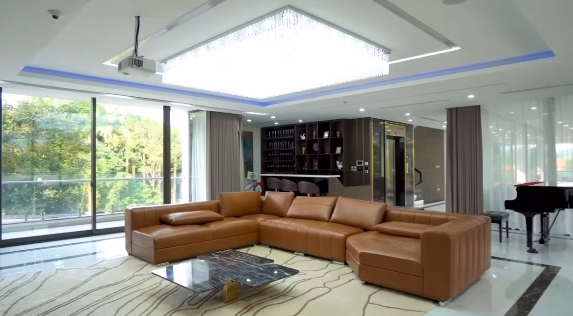 Phòng khách rộng mênh mông với sofa da và bàn mặt đá sang trọng. Ảnh chụp màn hình NhaTo