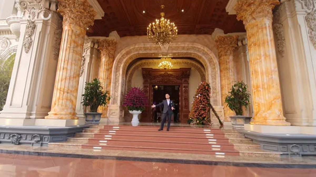 Sảnh đón khách tráng lệ với toàn bộ trần phía trên ốp gỗ và đèn chùm dát vàng. Ảnh chụp màn hình NhaTo