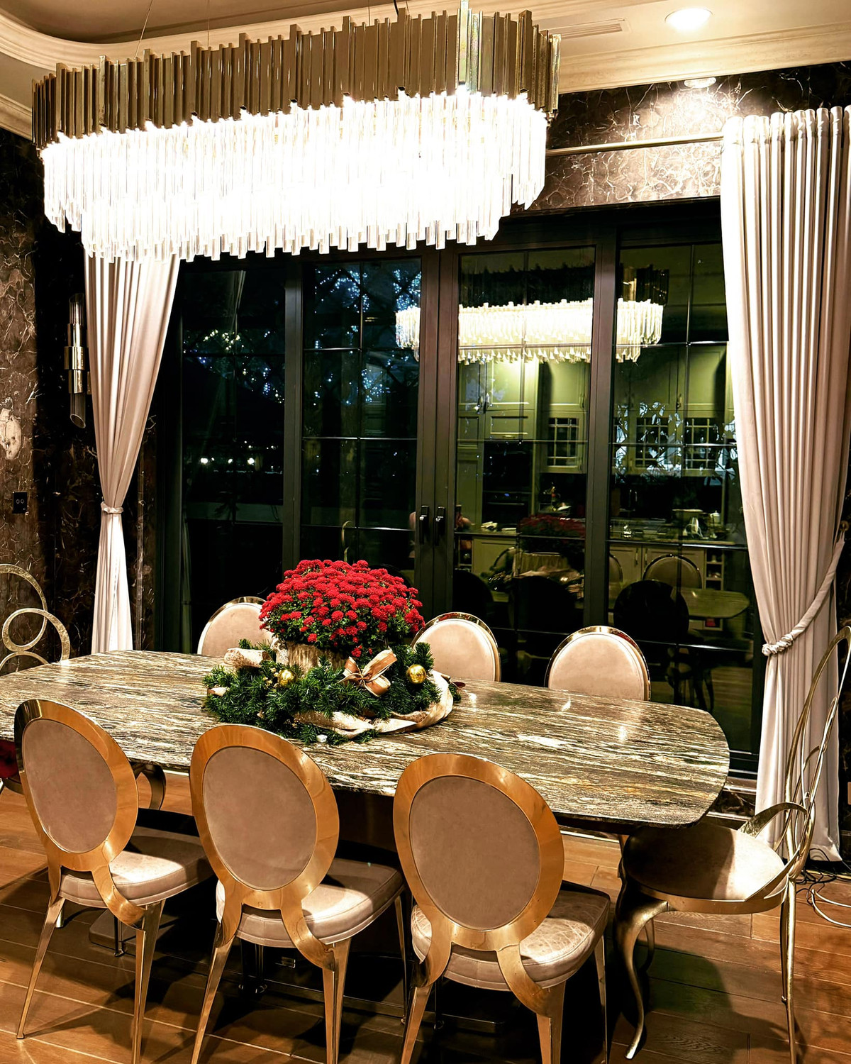 Phòng ăn sang trọng với bàn đá cẩm thạch kết hợp ghế bọc da khung vàng đồng với điểm nhấn là chậu hoa cúc đỏ và vòng trang trí Giáng sinh. Ảnh: FB Lã Thanh Huyền