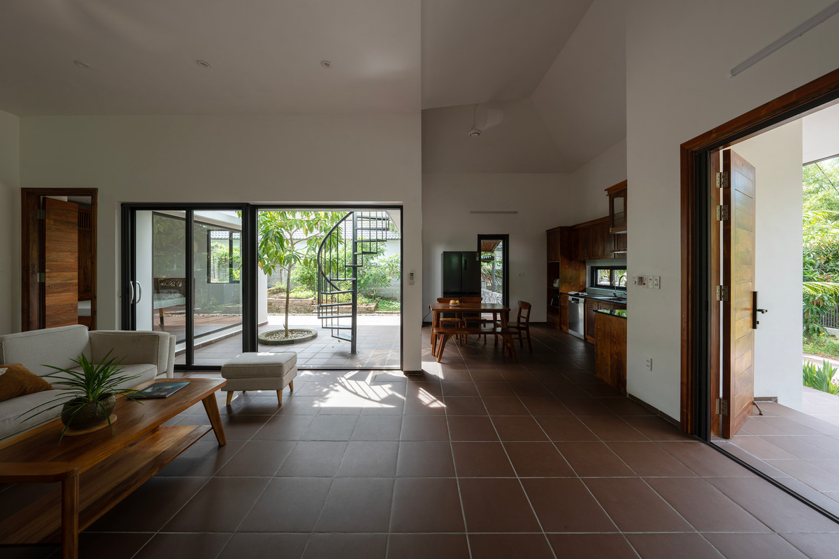 Không gian dưới mái hiên thiết kế giật cấp theo địa hình thoải dốc của khu đất, kết nối với một sân nhỏ, dẫn đến phòng khách, bếp và phòng ngủ. Ảnh: Cao Hoa