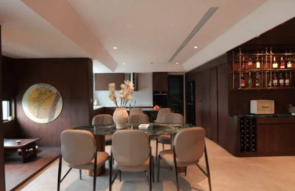 Khu vực bàn ăn thiết kế liên thông với phòng khách và bếp. Đặc biệt, bàn ăn, bàn trà và kệ ti vi đều sử dụng chất liệu đá màu xanh nhập khẩu từ Ý. Ảnh chụp màn hình