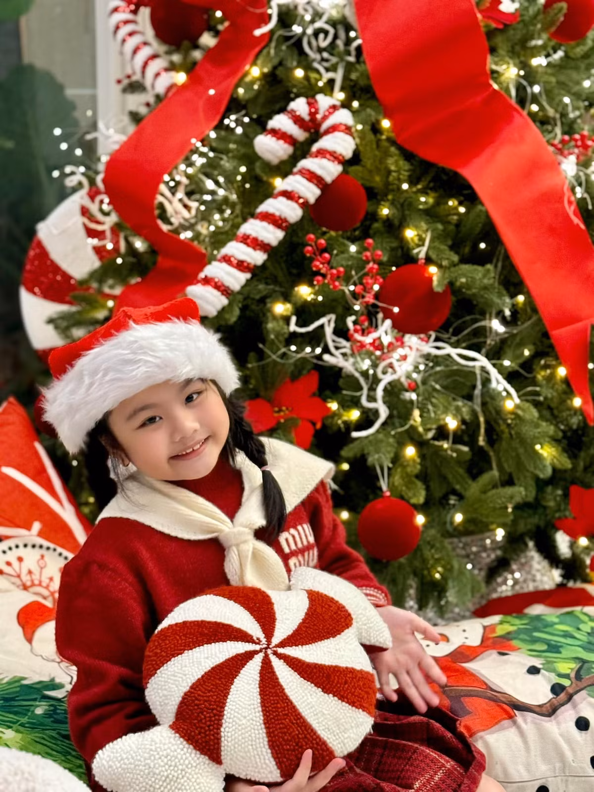 Cây thông trong phòng khách được trang trí đủ loại phụ kiện như nơ đỏ, quả cầu, kẹo xoắn, dây đèn led... Ảnh: FB Vân Trang