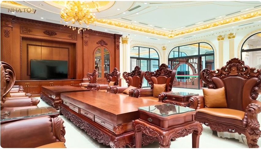 Bộ bàn ghế đồ sộ trong phòng khách bằng gỗ gõ đỏ. Ảnh chụp màn hình NhaTo
