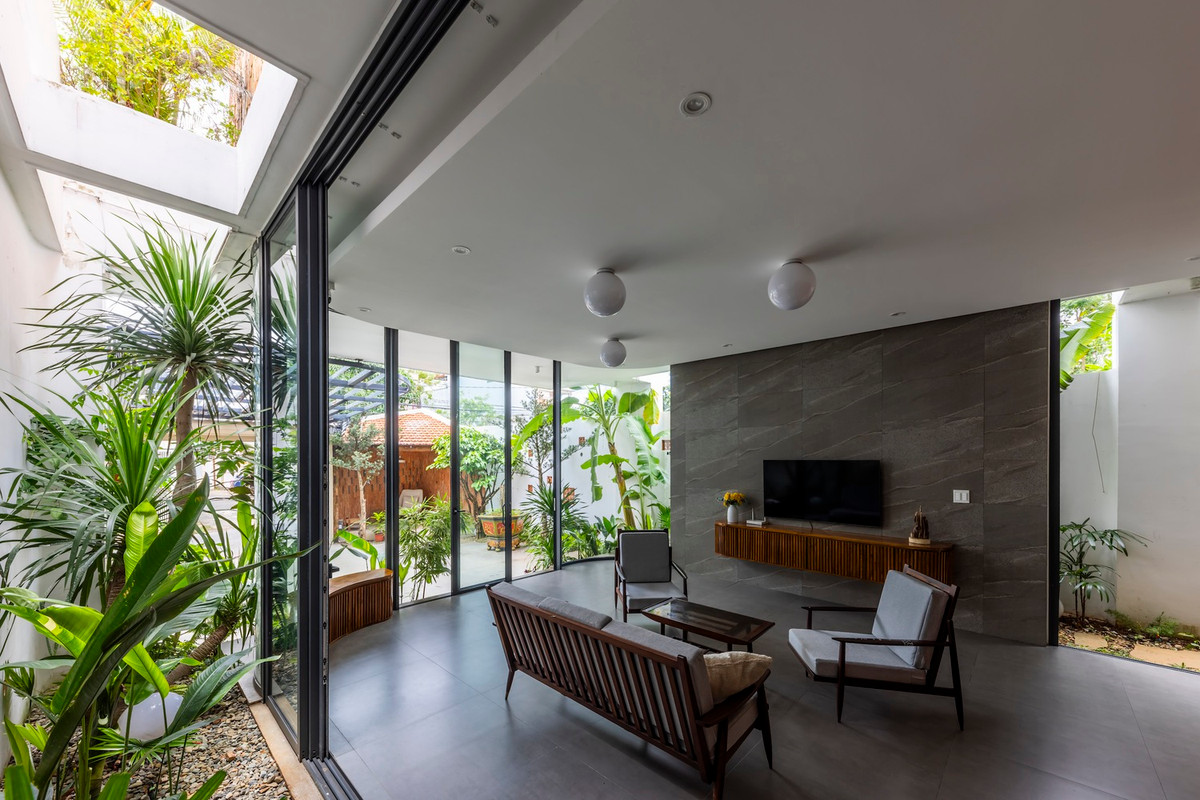 Bước vào bên trong, phòng khách là một không gian mở, kết nối trực tiếp với khu vườn xanh tươi bên ngoài thông qua những cánh cửa kính lớn. Ảnh: Hiroyuki Oki