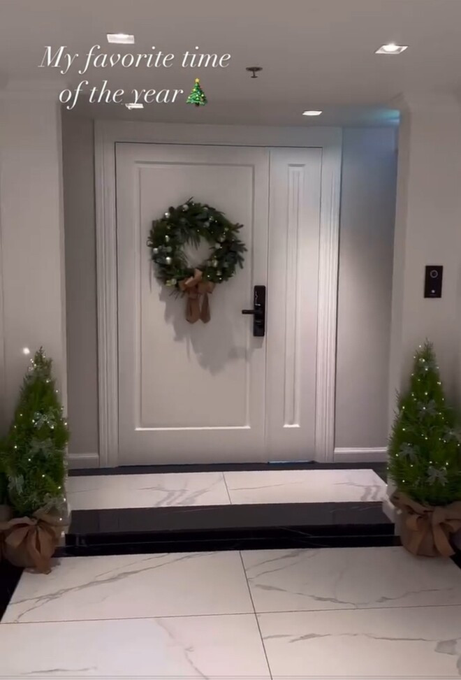 Cửa chính được tô điểm bằng vòng nguyệt quế lớn và hai cây thông nhỏ hai bên. Ảnh chụp màn hình