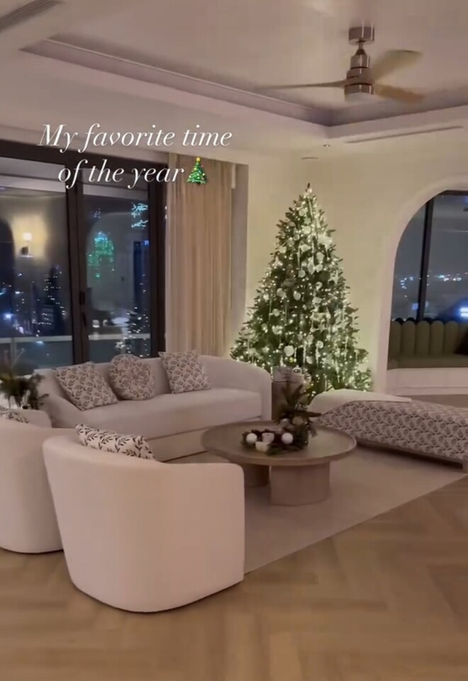 Phòng khách nổi bật với cây thông Noel lớn cùng phụ kiện trắng lấp lánh, bộ sofa dáng bo tròn. Ảnh chụp màn hình