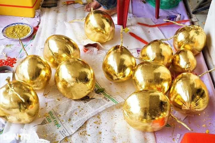 Sau khi chọn được dừa, nghệ nhân quét keo đều khắp trái, sau khoảng 35-40 phút keo khô thì dán lá vàng lên. Ảnh: Facebook