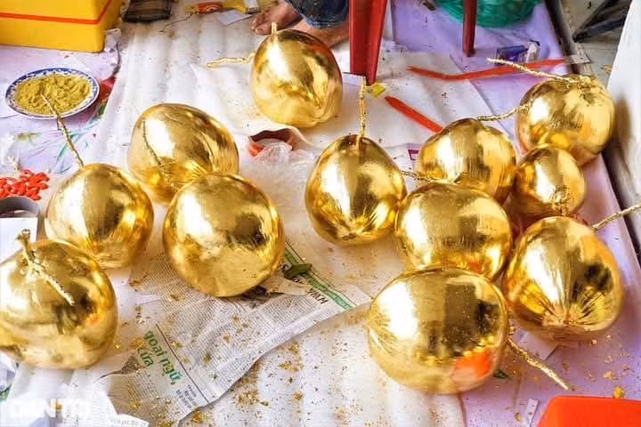 Sau khi chọn được dừa, nghệ nhân quét keo đều khắp trái, sau khoảng 35-40 phút keo khô thì dán lá vàng lên. Ảnh: Facebook