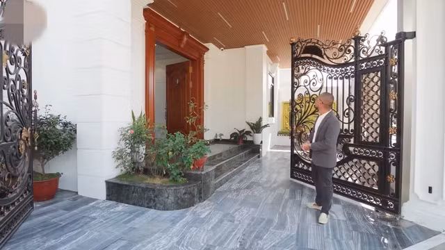 Cổng vào bề thế với những thanh sắt đặc và gia công hoàn toàn bằng thủ công. Các thanh sắt được uốn dựa theo thiết kế của cửa và có lớp sơn giả đồng. Ảnh chụp màn hình