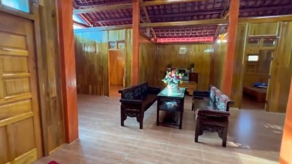 Khu vực sinh hoạt chung nổi bật với bộ bàn ghế tối màu được làm từ gỗ gụ, đồng điệu với ngôi nhà. Ảnh chụp màn hình