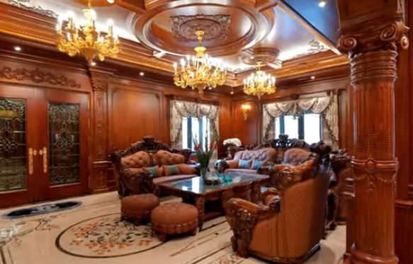 Phòng khách hoành tráng với bộ sofa bằng gỗ mun, chạm trổ họa tiết hình chú voi. Ảnh chụp màn hình NhaF
