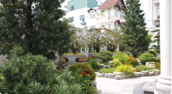 Khu vườn ngập tràn cây cối, có tùng, có các loại hoa... Ảnh chụp màn hình NhaTo