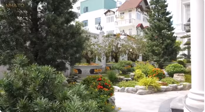 Khu vườn ngập tràn cây cối, có tùng, có các loại hoa... Ảnh chụp màn hình NhaTo