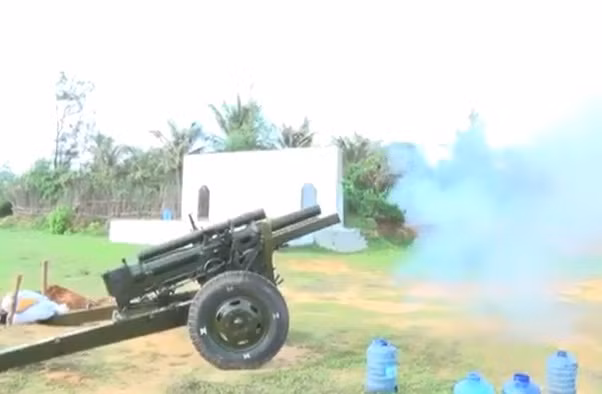Lượng nước này đã được các nhà sản xuất pháo tính toán để khi đưa vào nòng pháo trong quá trình bắn, pháo hoạt động như khi bắn đạn thật. Khi bắn, các pháo thủ vẫn thao tác giống như bắn đạn thật và bắn liên thanh được 2 viên. Ra khỏi nòng, đầu đạn gỗ sẽ vỡ, không gây sát thương; nước thì bắn tung tóe giống như… pháo hoa vậy. Trong ảnh, bắn đạn nước từ lựu pháo 105mm sau khi sửa chữa. Nguồn ảnh: Truyền hình Quân khu 7