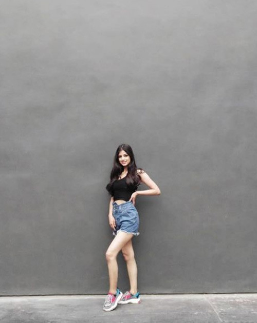 Người đẹp sinh năm 2000 khoẻ khoắn với quần short jeans, áo crop top và giày thể thao.