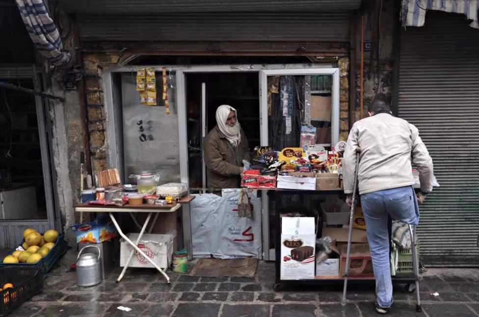 Người đàn ông khuyết tật mua hàng tại một quầy tạp hóa ở Aleppo.