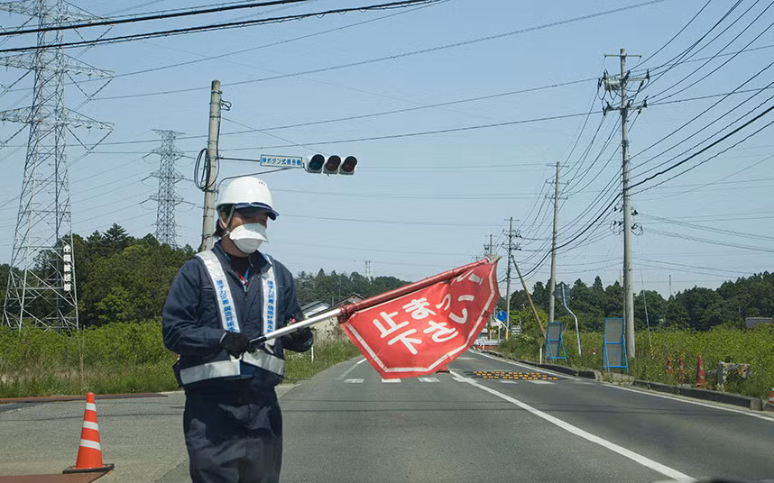 Một nhân viên bảo vệ đứng kiểm tra giấy phép vào "vùng cấm" trong thị trấn Fukushima.