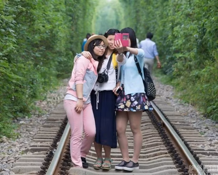 Chụp ảnh “tự sướng” trên đường ray chạy qua đường hầm cây xanh sau đó đã thành một trào lưu mới của giới trẻ Trung Quốc.