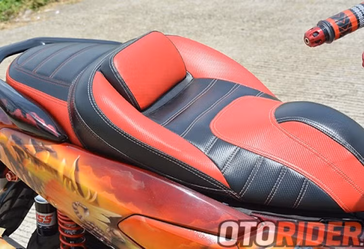 Tương tự như thân xe, bộ yên của chiếc Nmax cũng đã được bọc lại hoàn toàn trong da với tông màu đỏ đen. Đệm mút của yên cũng đã được thay thế và tạo hình lại với các dải đệm đỡ êm ái, khiến chiếc maxi scooter cỡ nhỏ này càng trở nên êm ái hơn.