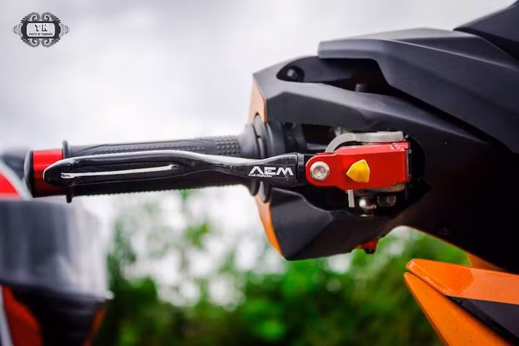 Ở hai đầu tay lái, chủ xe đã lắp cho chiếc xe côn tay Winner cặp gù Rizoma, bên cạnh đó là cặp tổng phanh và côn AEM với tay bằng sợi carbon. Được biết cặp tay này có trị giá khoảng 10 triệu đồng.