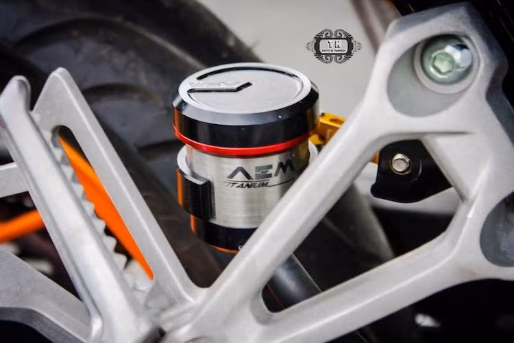 Ở phía sau, thương hiệu AEM tiếp tục được lựa chọn với bình dầu rời cho phanh sau bằng titan, được bắt vào xe thông qua pát Rizoma màu vàng nổi bật.