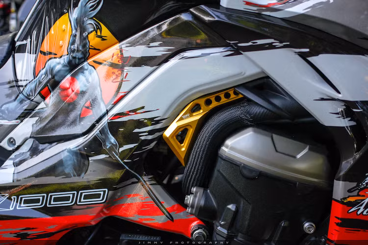 Một chi tiết khá độc đáo của chiếc Z1000 này đó là miếng che hệ thống phun nhiên liệu điện tử của hãng DMV, không chỉ có tác dụng bảo vệ hệ thống phun xăng của xe mà còn trang trí cho xe do được CNC từ nhôm và nhuộm màu vàng đẹp mắt.