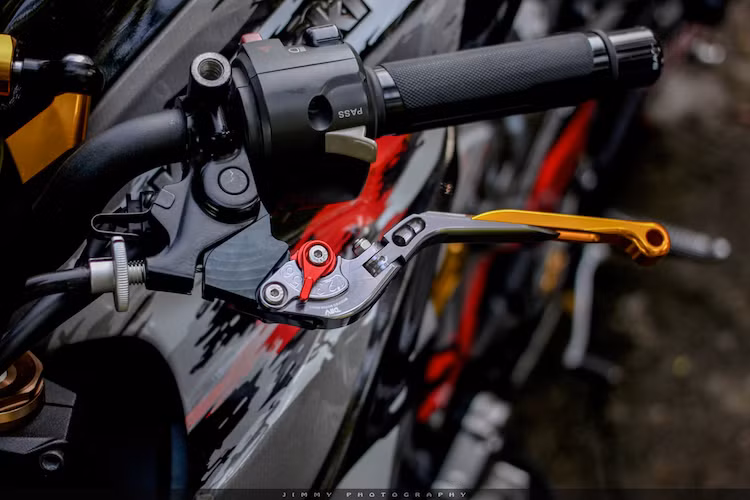 Ở hai bên tay phanh và côn là sự xuất hiện của cặp tay nhôm của hãng DMV, không chỉ có khả năng điều chỉnh khoảng hành trình với 6 cấp độ mà còn có thể chỉnh độ dài tay và có bản lề gấp để chống gãy tay khi xe gặp tai nạn.