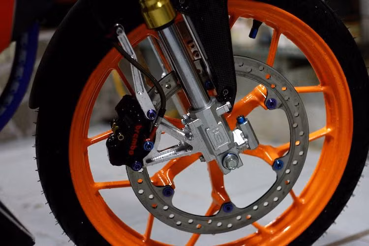 Bộ mâm 6 cánh kép đặc trưng của Sonic và Winner, kèm theo đĩa phanh trước cũng được giữ lại. Tuy nhiên, heo phanh của xe đã được nâng cấp lên loại Brembo với pát nhôm CNC gắn dọc đầy chắc chắn. Chắn bùn trước của xe cũng đã được dán carbon đẹp mắt.