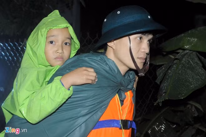 Dân quân xã Phước Thuận (huyện Tuy Phước, tỉnh Bình Định) giúp bà con thôn Phổ Trạch sơ tán trẻ em từ vùng trũng đến ở xen ghép nhà dân vùng cao tránh lũ an toàn.