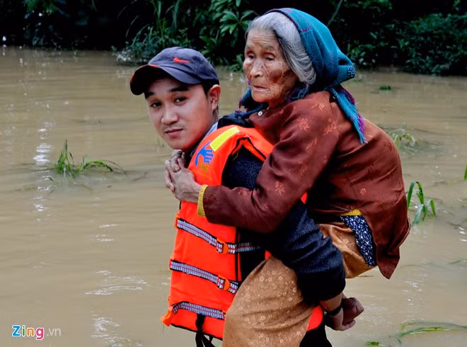 Dân quân cõng cụ Nguyễn Thị Nghệ (92 tuổi, thôn Mỹ Hòa, xã Nghĩa Mỹ, huyện Tư Nghĩa) đến nơi an toàn. "Ở tuổi gần đất xa trời nhưng từ trước đến giờ, tôi chưa bao giờ thấy lũ lớn dồn dập tràn về dày đặc như những ngày qua. Chưa kịp mừng đợt lũ này rút thì trận lũ sau lại ập đến, may nhờ các chú dân quân giúp đỡ đưa đi sơ tán chứ không biết xoay sở làm sao", cụ Nghệ nói.